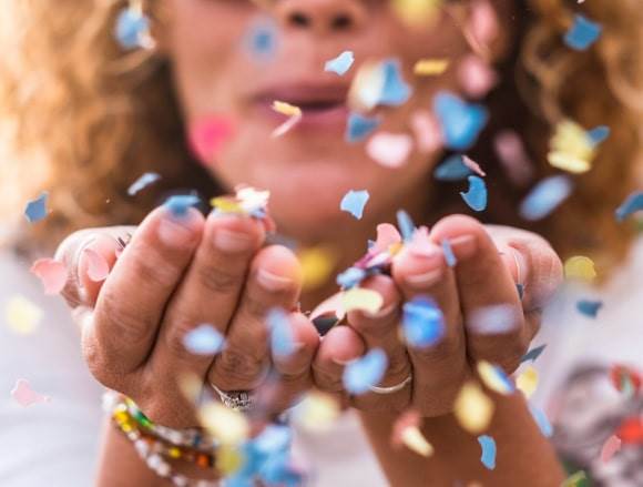 Be So Well - Wellness Celebration - woman blowing confetti
